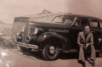 Albumfoto van een man bij een auto uit de jaren dertig
