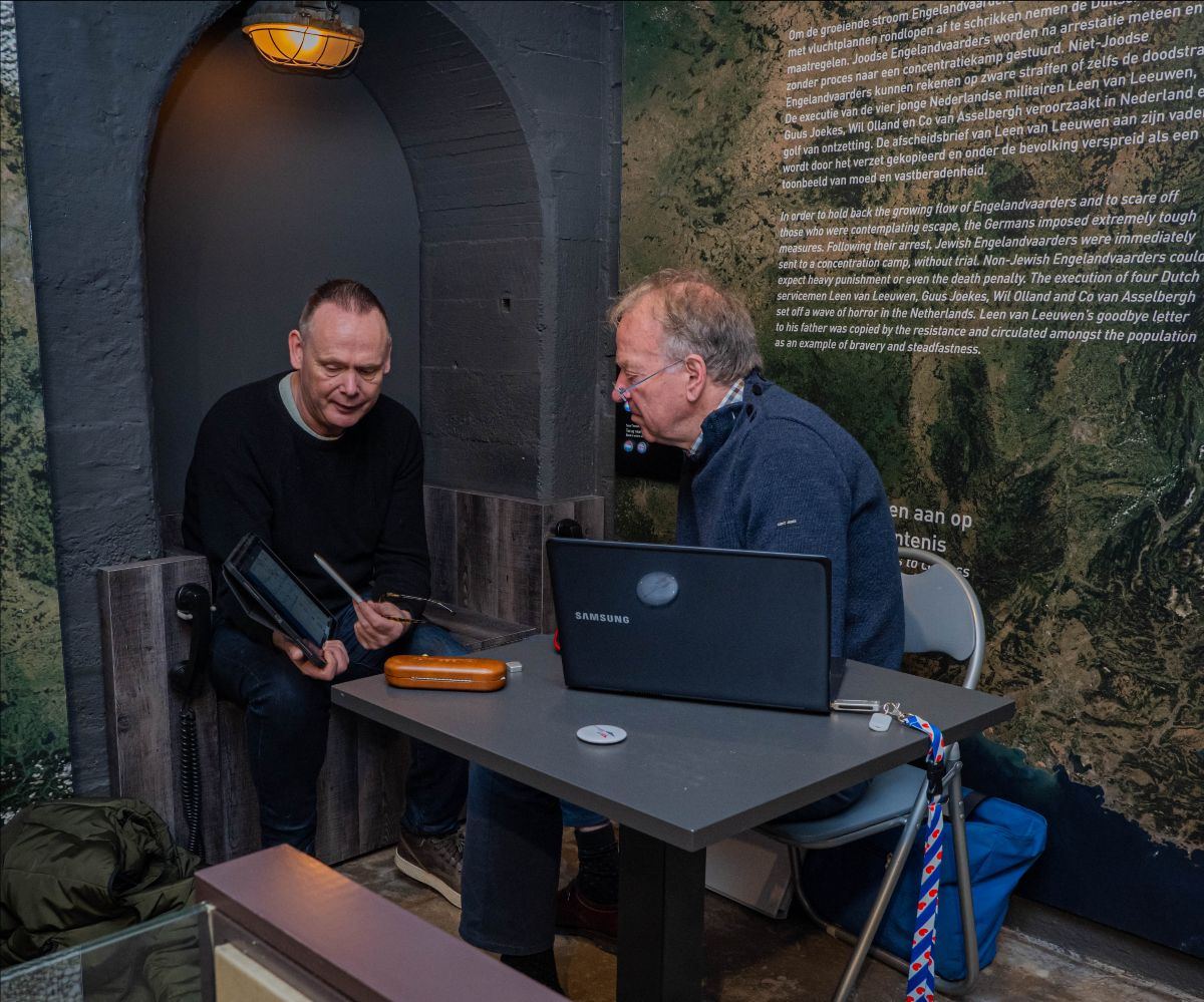 Twee mannen aan een tafel met een laptop in de bunker