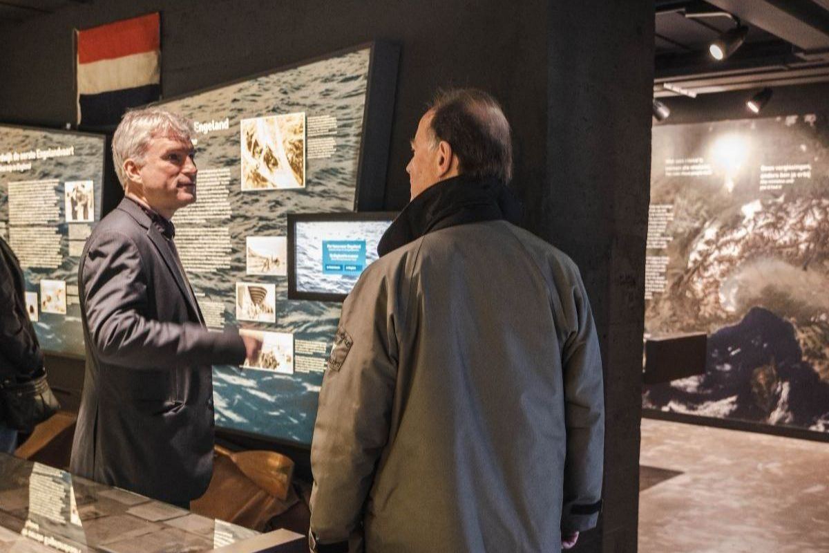 Twee mannen bekijken de wandpanelen en beeldschermen in de museumzaal