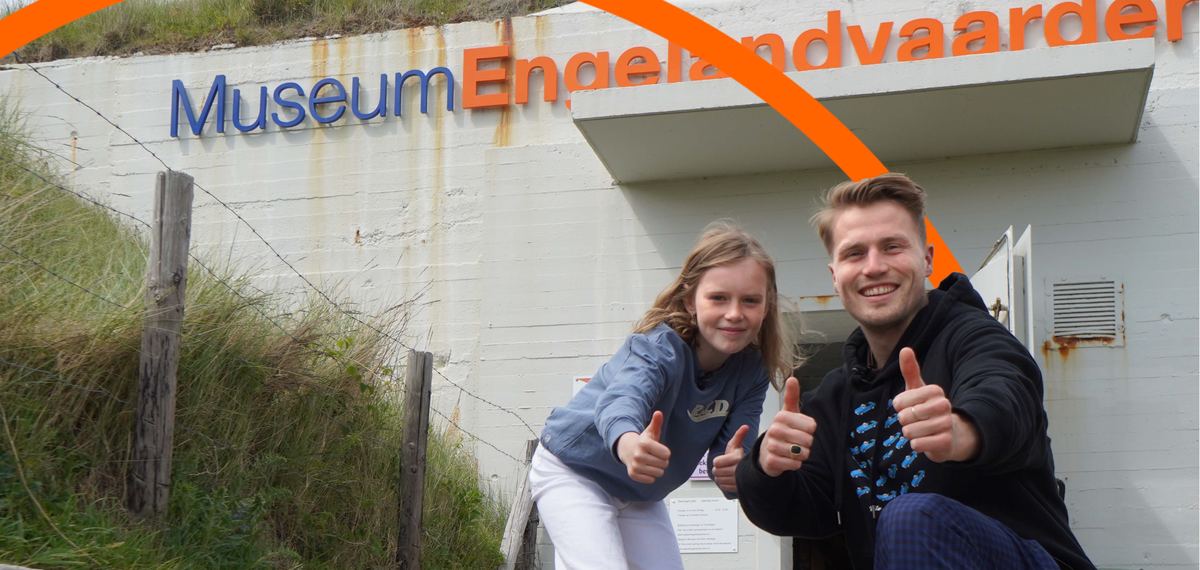 Een meisje en een man steken hun duim op voor de gevel van het museum