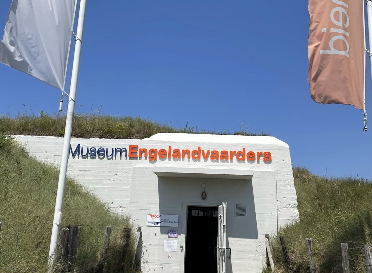 De ingang van Museum Engelandvaarders in de duinen, met vlaggen naast de bunker