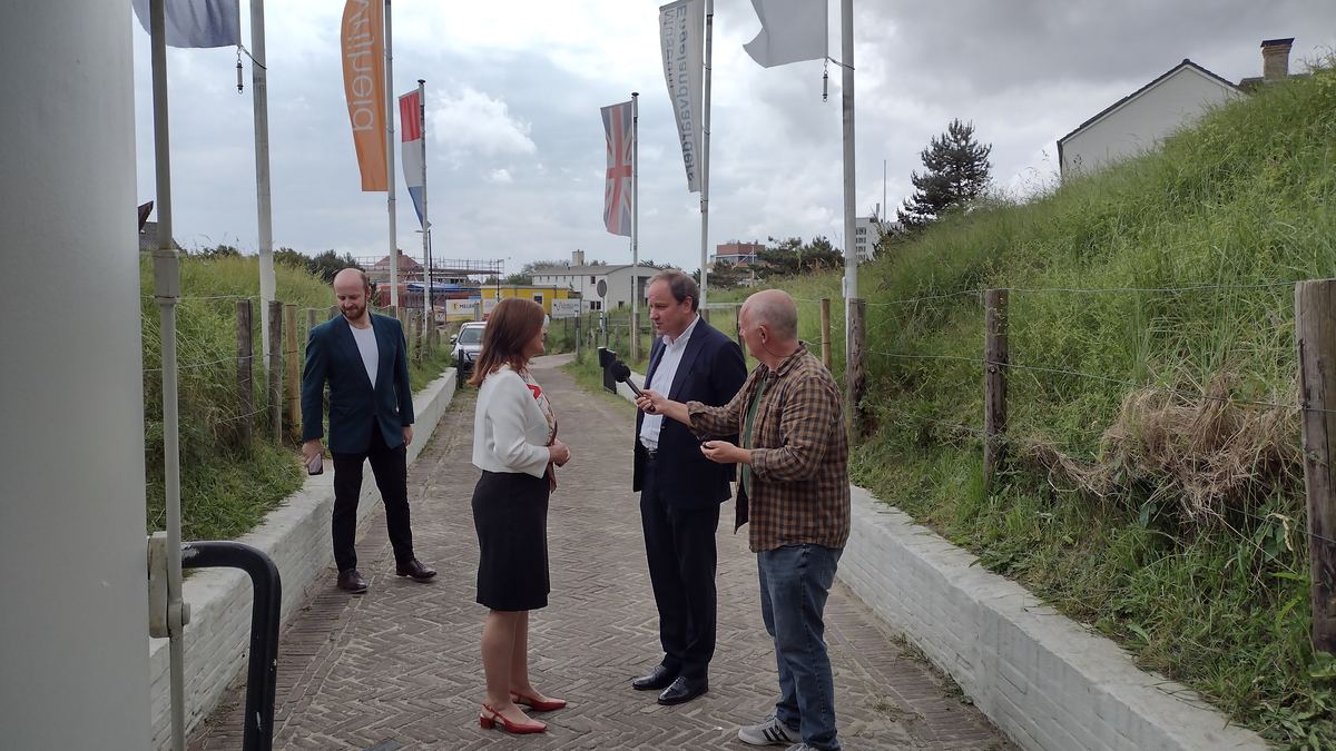 Vier mensen in gesprek op het pad naar het museum, met vlaggen langs de route